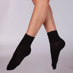 A pair of black essential dance socks worn on the lower legs, positioned in a standing pose.