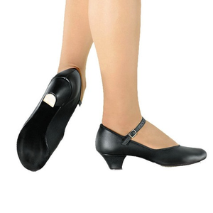 A black suede character shoe with a low heel and ankle strap, worn by a person standing on their tiptoe.
