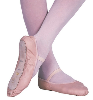 A pair of pink full sole leather ballet slippers worn by a child.